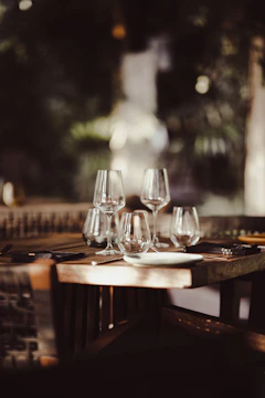 Close-up of a rustic wooden table set with beautifully plated artisanal dishes and a warmly lit restaurant interior in the background.