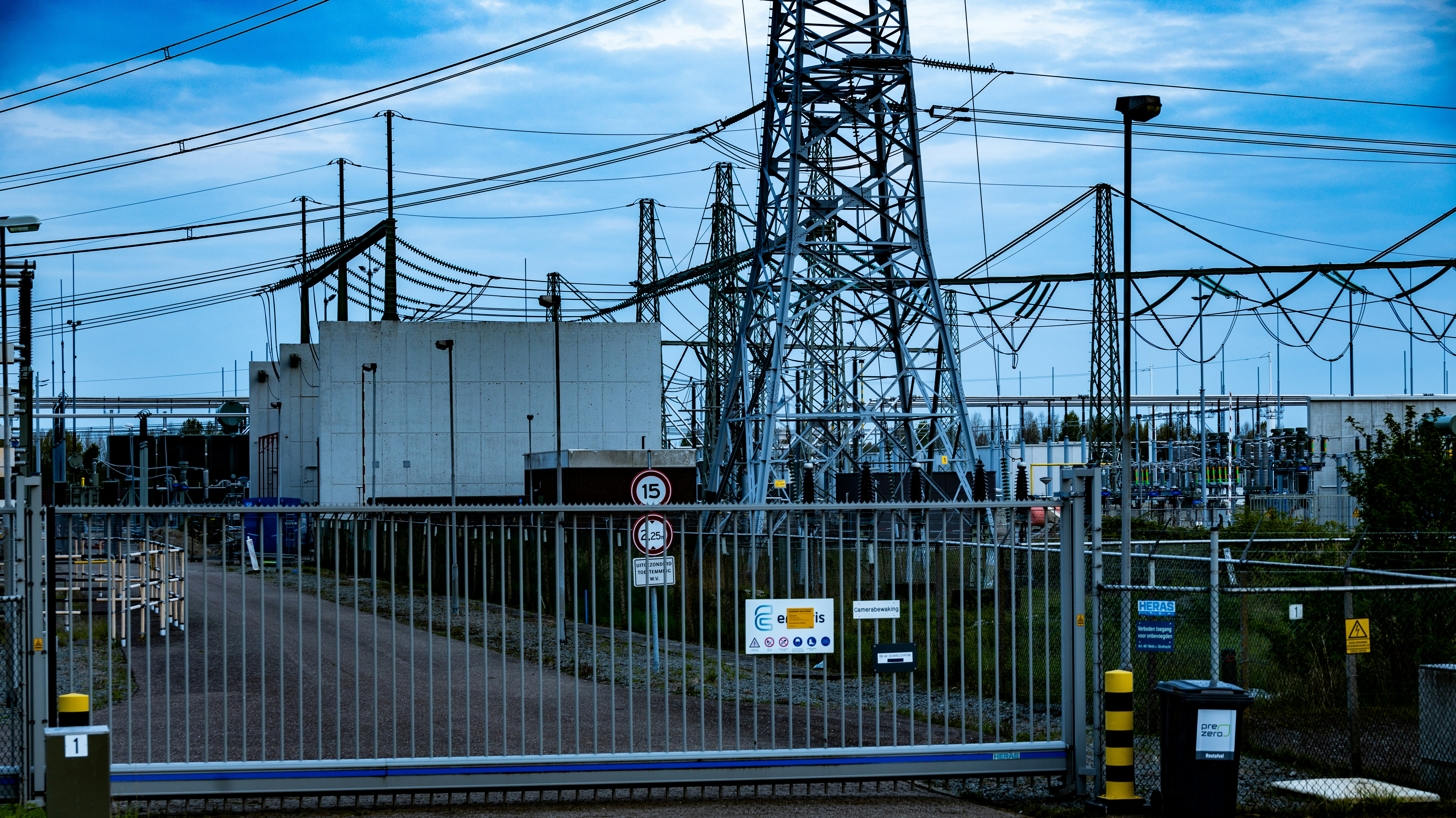 High-voltage electrical transmission towers with aluminum cables against clear blue sky industrial setting