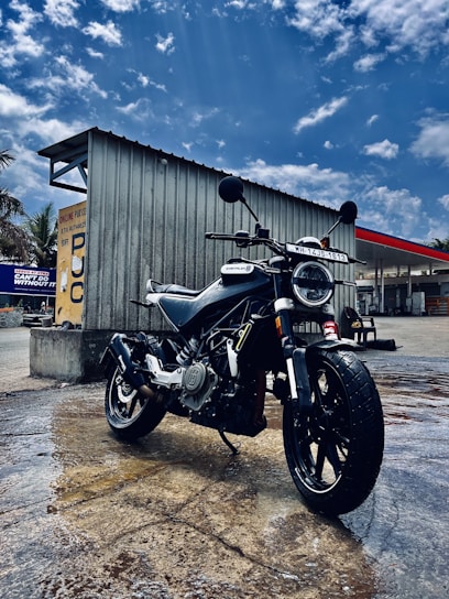 Sleek electric motorcycle parked by a rainy urban street, water droplets glistening on the surface