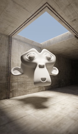 A 3D-rendered monkey head, stylized and cartoonish, floats in a concrete room with a skylight opening showing a clear blue sky. The setting is minimalist with stark shadows.
