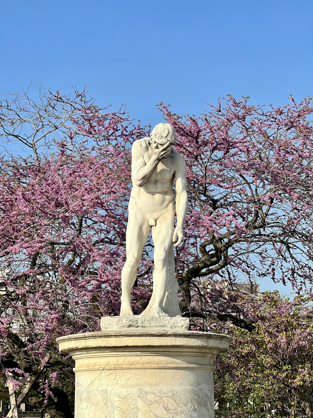 uma estátua de um homem em pé na frente de uma árvore