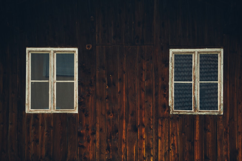 two windows on the side of a wooden building