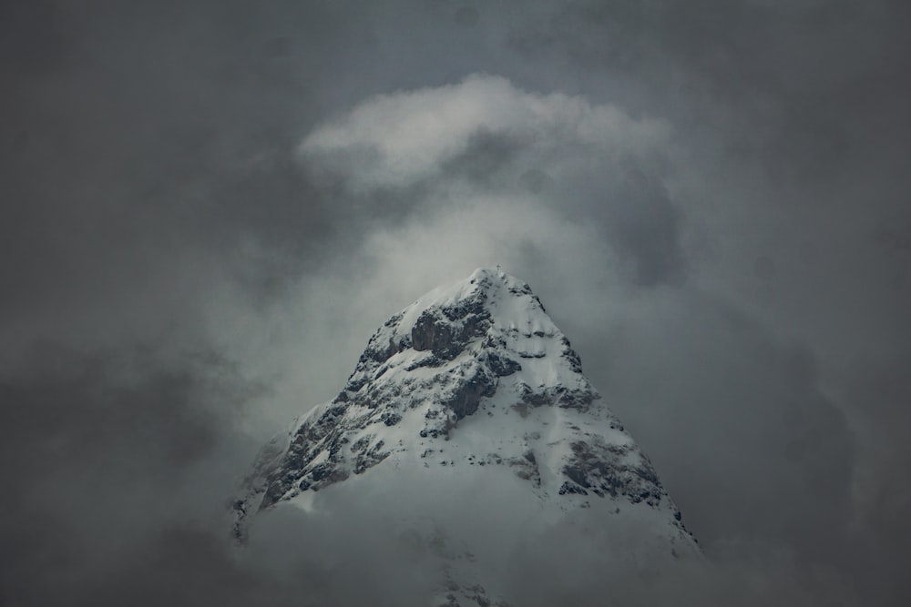 a very tall snow covered mountain under a cloudy sky