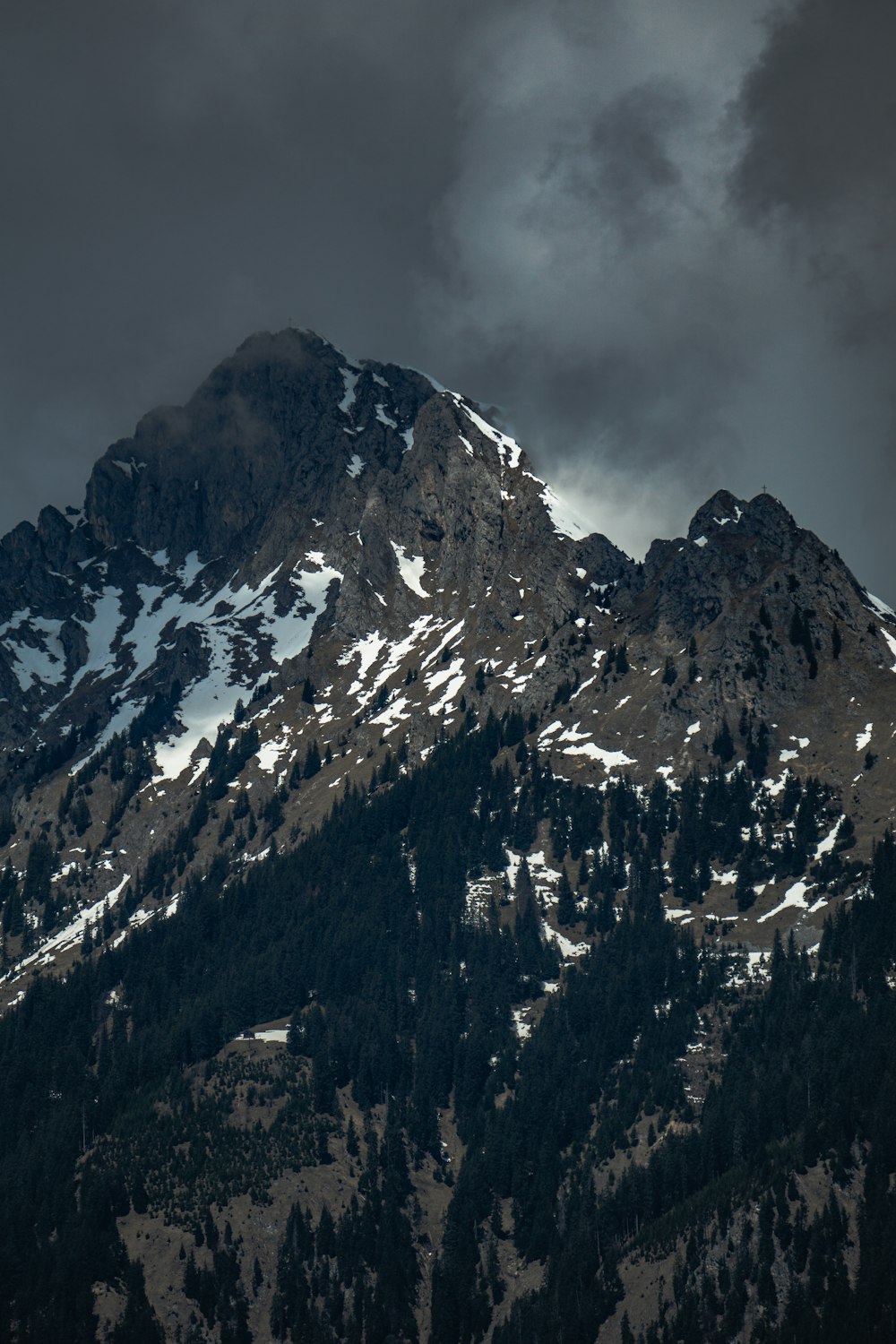 a large mountain covered in snow under a cloudy sky