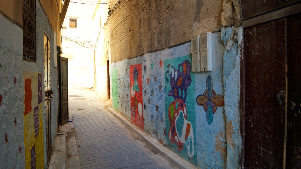 a narrow alley with a painted mural on the wall
