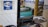 A vintage cash register is prominently positioned on a reflective surface next to a metal tray. A blue sign indicates the availability of WiFi. The setting includes ornate wall tiles and reflections of chairs and decor in the background, suggesting a cozy interior space.