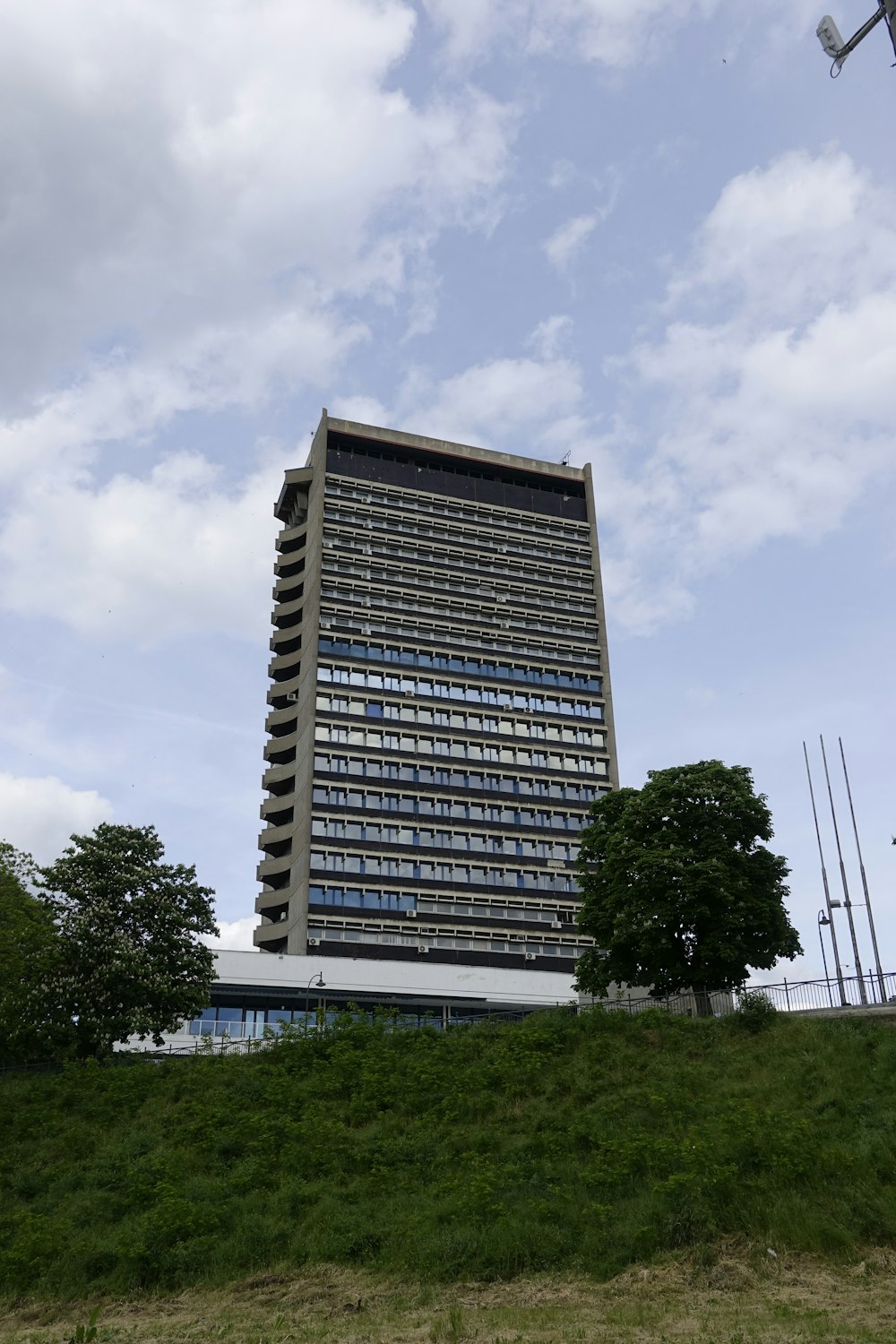 a tall building sitting on top of a lush green hillside