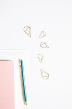 Minimalist desk with neat notebooks and a gold pen on soft cream background
