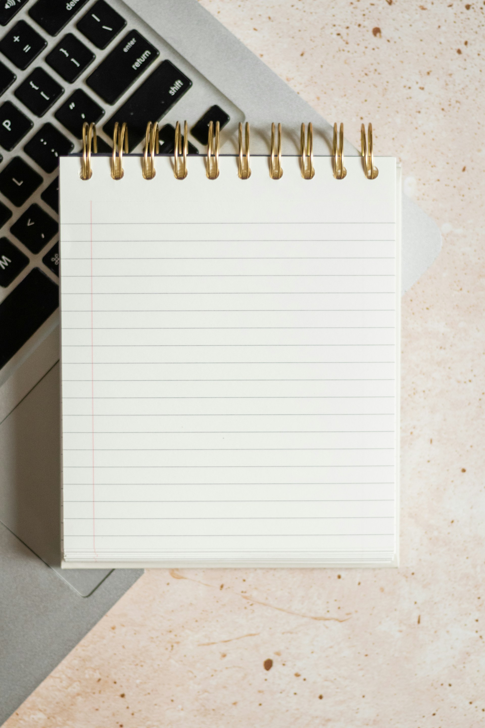 a notepad sitting on top of a laptop computer next to a keyboard