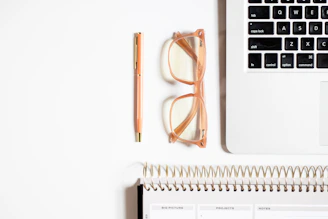A calm workspace with a notebook, glasses, and a laptop displaying organized workflow charts.