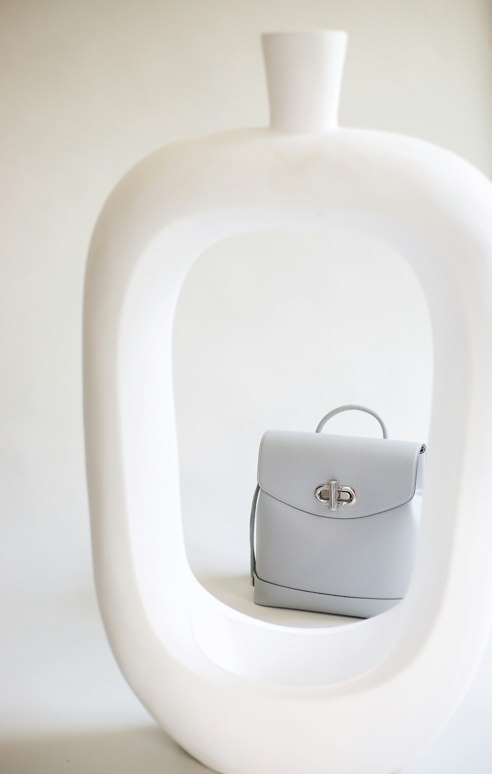 a white purse sitting on top of a white sculpture