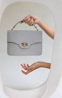 a woman's hand holding a gray purse