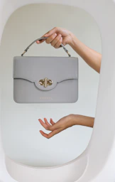 a woman's hand holding a gray purse