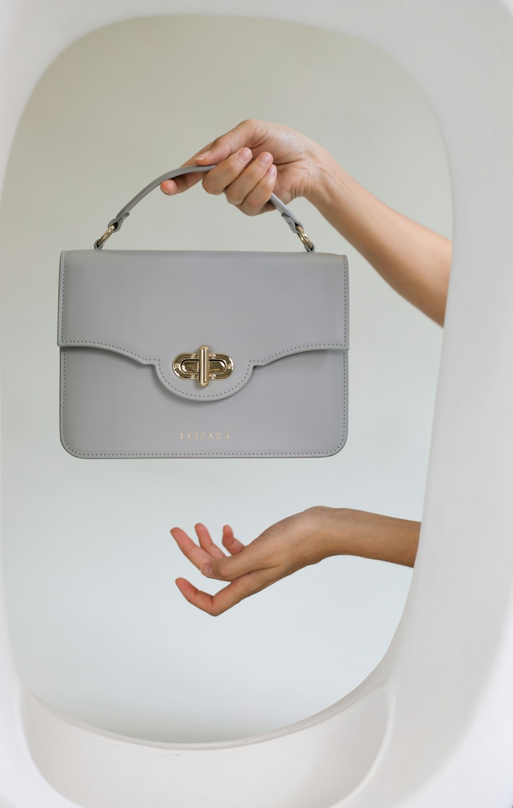a woman's hand holding a gray purse