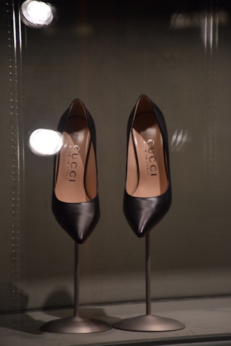 Elegant formal shoes polished and displayed on a glass stand.