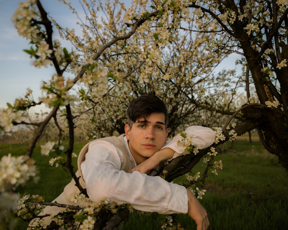 a young man leaning on a tree branch