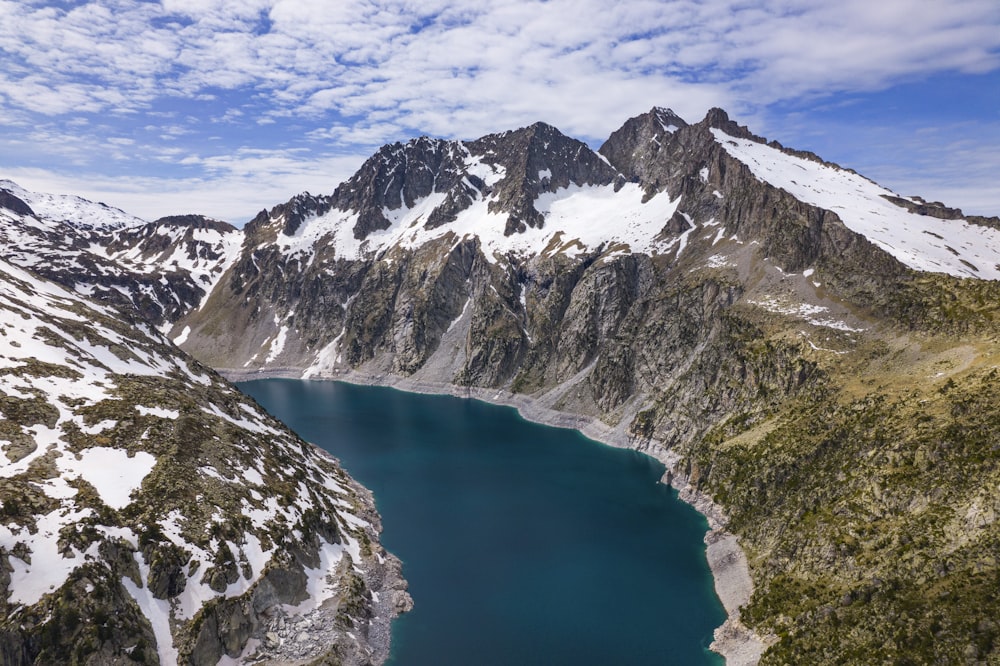 a lake surrounded by snow covered mountains under a blue sky