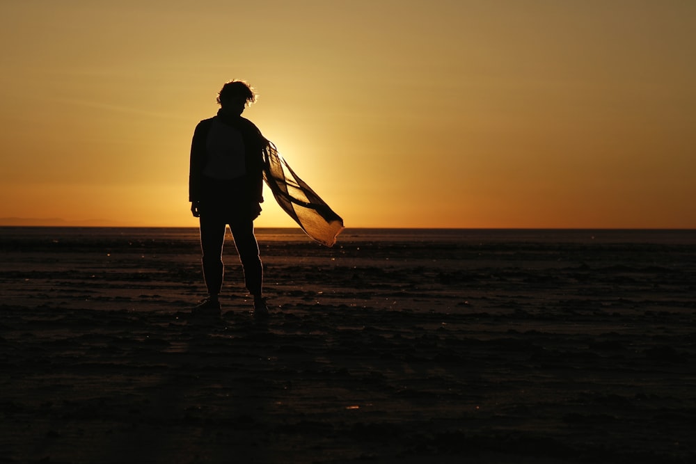 a person standing on a beach holding a surfboard