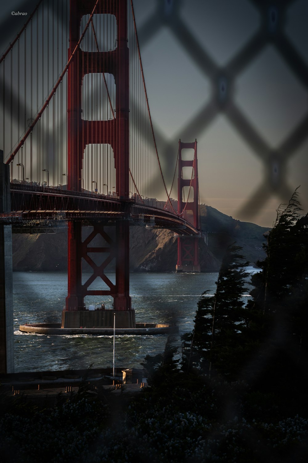 a view of the golden gate bridge through a chain link fence