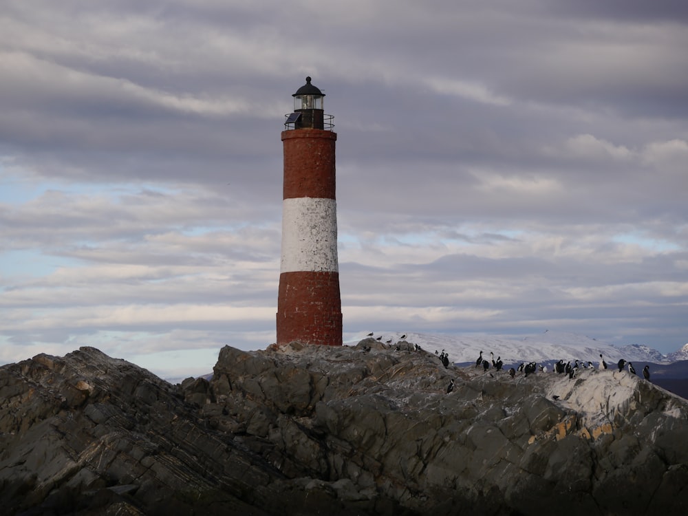 a red and white lighthouse sitting on top of a rocky hill