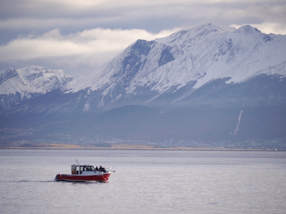 a red boat floating on top of a large body of water