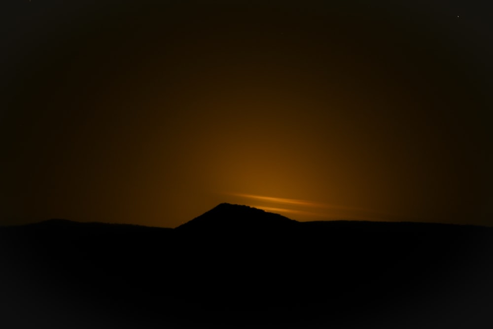 the sun is setting over a mountain in the distance
