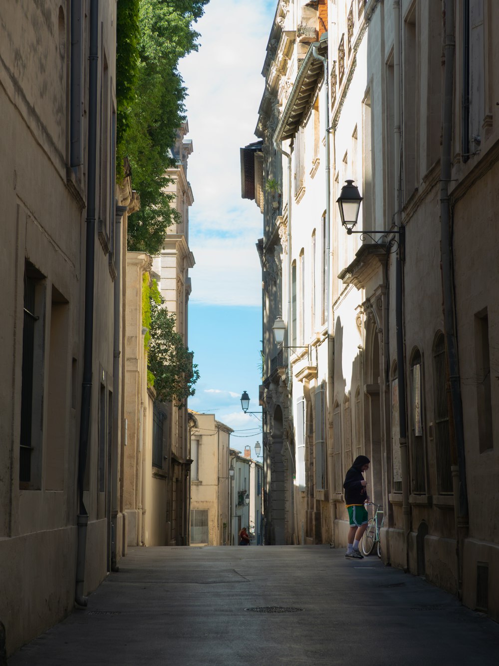 a couple of people walking down a street next to tall buildings