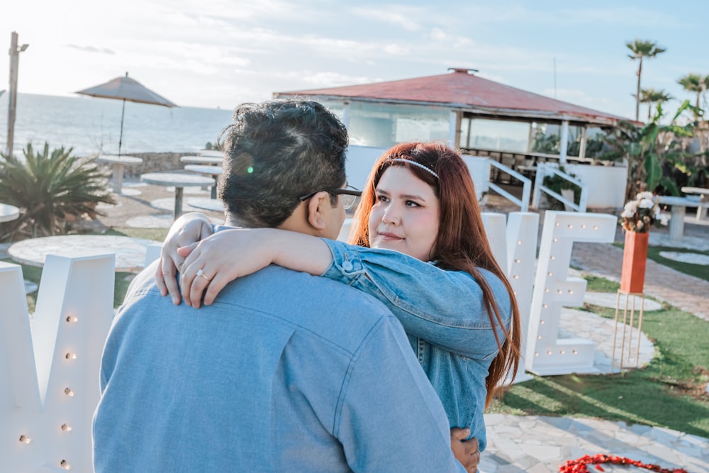 a man and a woman embracing each other in front of the ocean