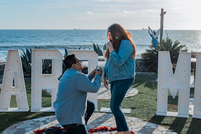 a man taking a picture of a woman in front of the ocean