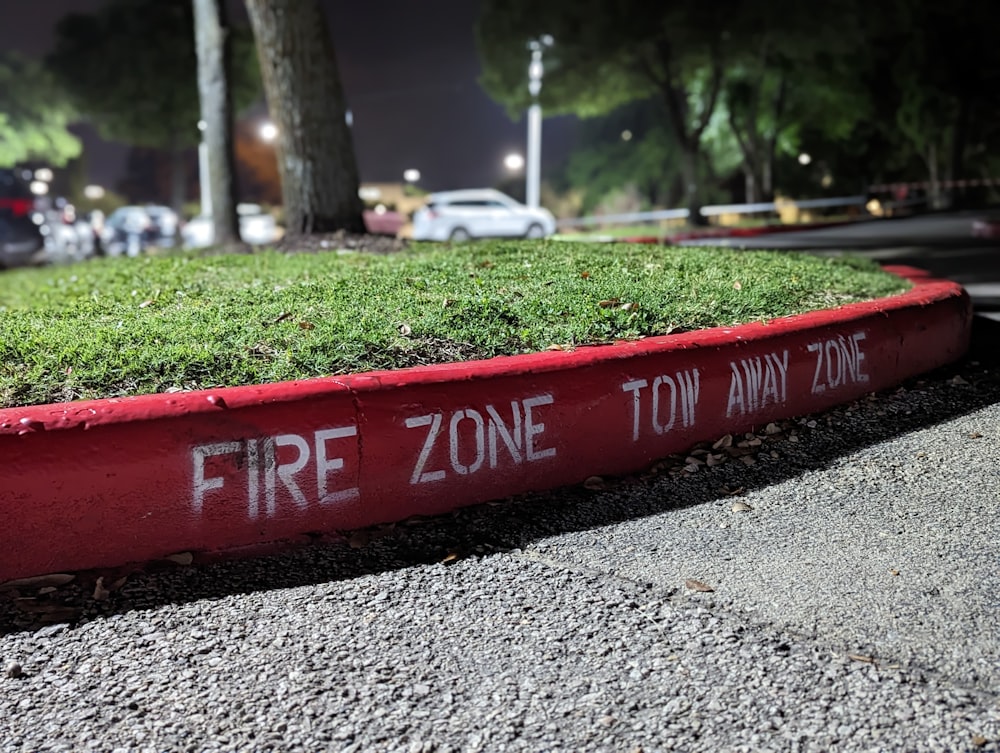 a red fire zone sign sitting on the side of a road