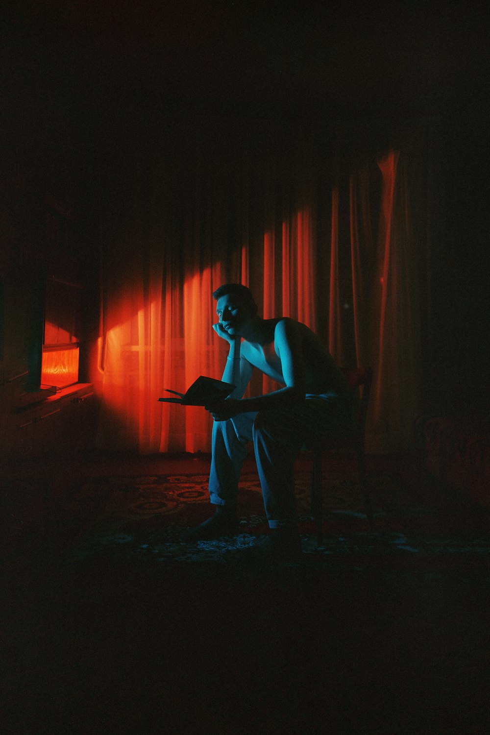 um homem sentado em uma cadeira em um quarto escuro