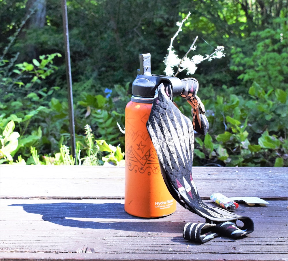 an orange water bottle and an orange water bottle on a wooden table