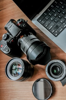 a camera sitting on top of a wooden table next to a laptop