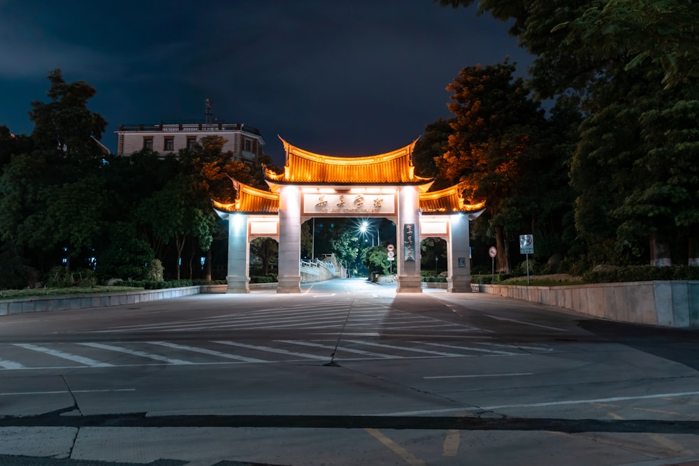 an empty parking lot at night with a lit archway