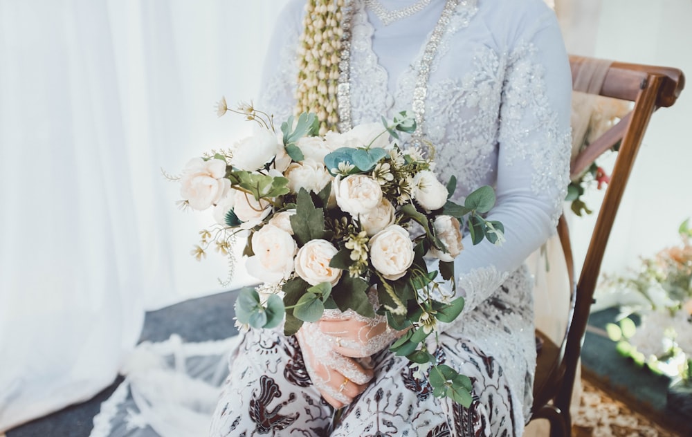 a woman sitting in a chair holding a bouquet of flowers