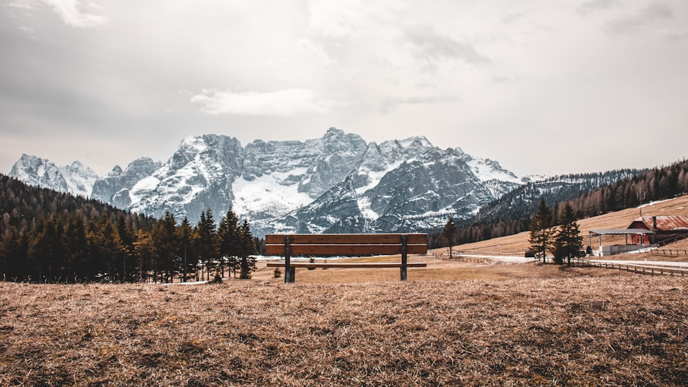 a wooden bench sitting on top of a grass covered field