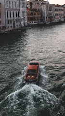 A turquoise-hued electric canal boat gliding smoothly along a serene canal at sunset