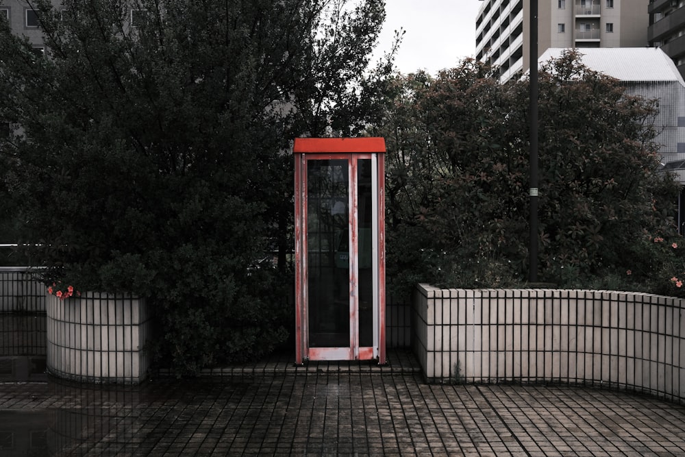 a red phone booth sitting on top of a brick sidewalk