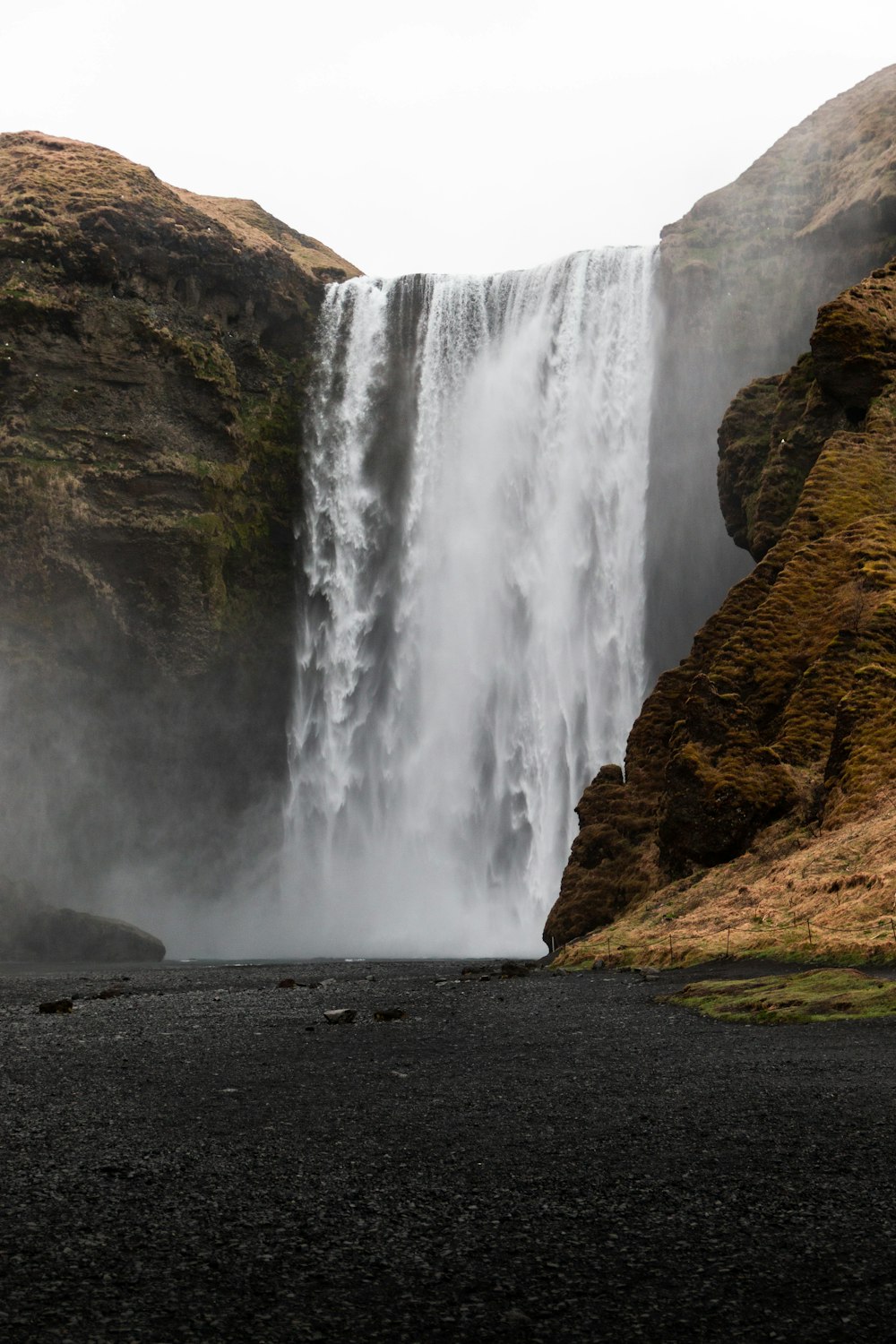 a large waterfall with a man standing in front of it