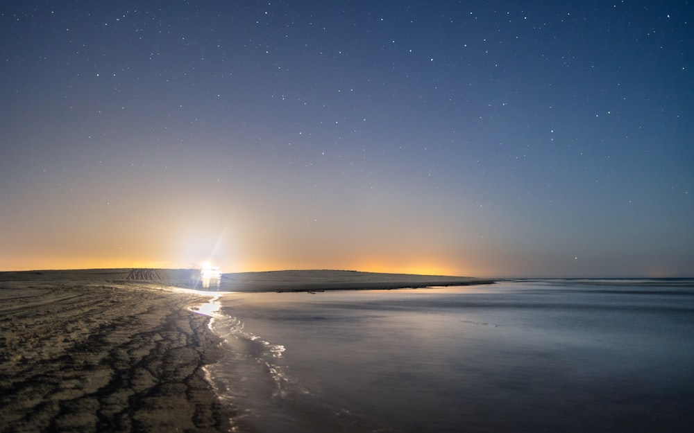 a night time view of a beach with stars in the sky