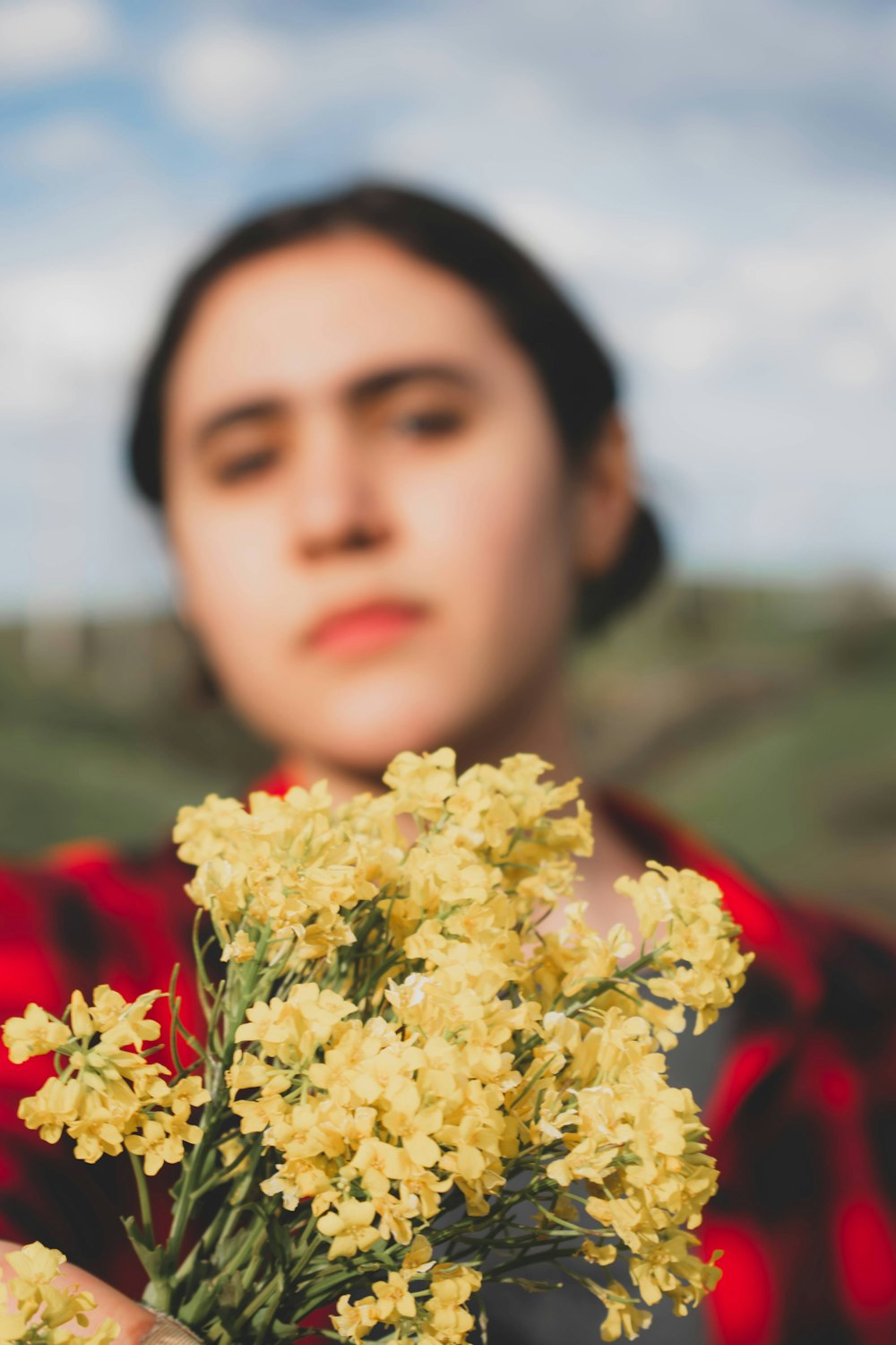 a woman holding a bunch of yellow flowers