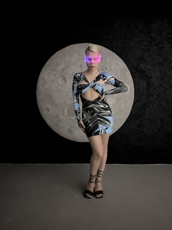 A model posing against a graffiti wall wearing layered futuristic rave clothing with glowing accents.