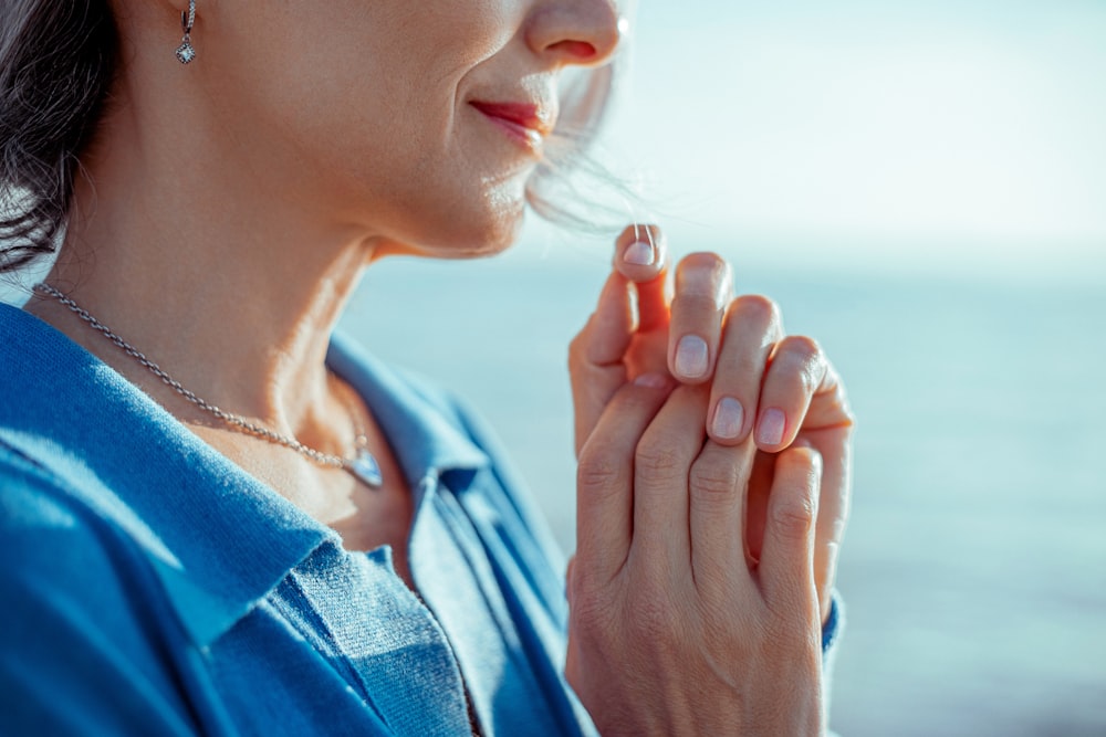 a woman holding her hands together in prayer