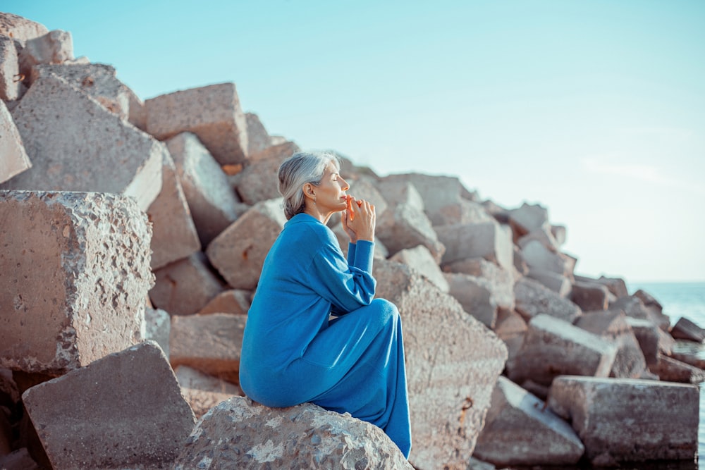 Eine Frau, die auf einem Felsen neben dem Meer sitzt