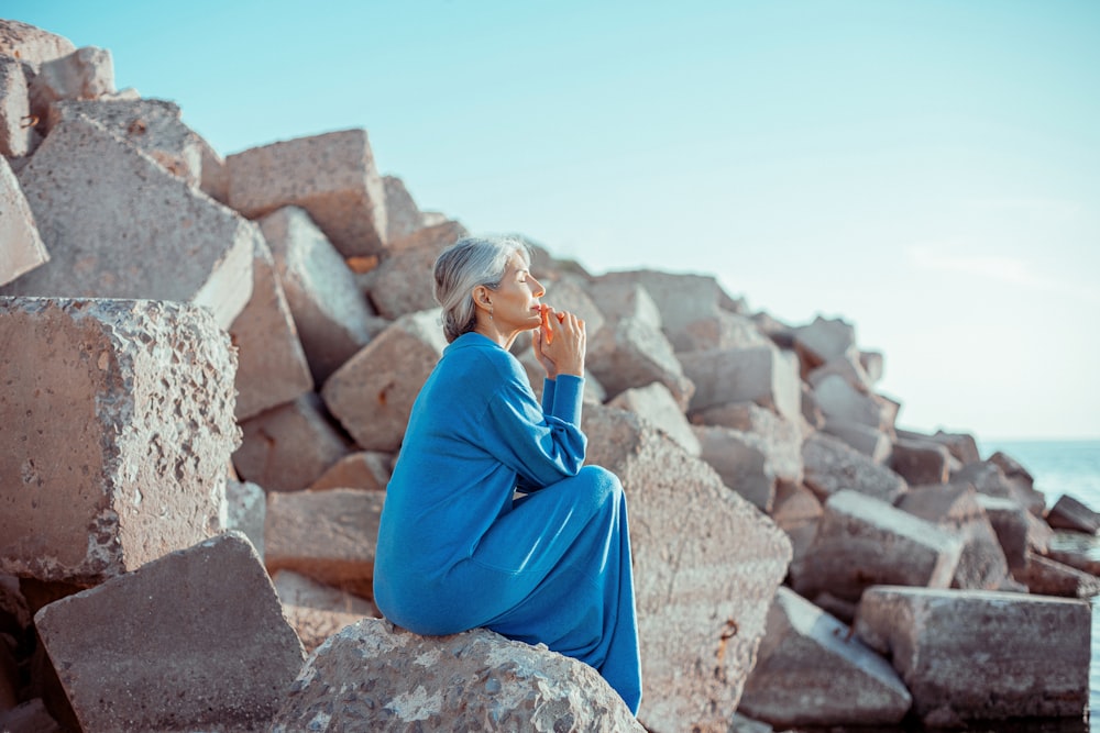 a woman sitting on a rock next to the ocean