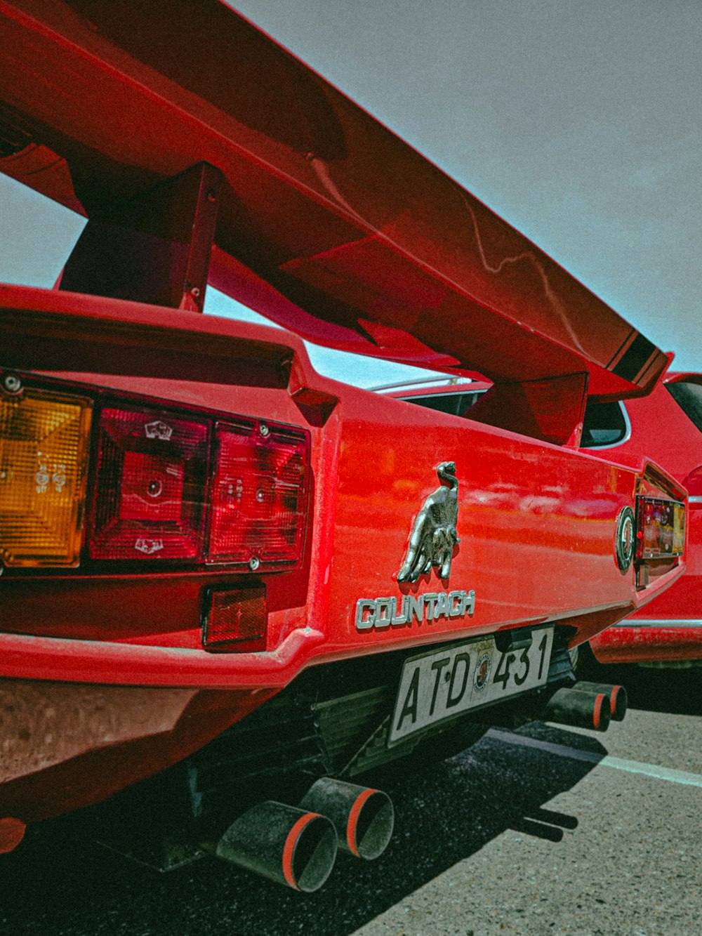 a red car parked in a parking lot next to another car