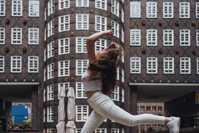 A dynamic dancer mid-air performing a hip hop freeze against a neon-lit urban backdrop.
