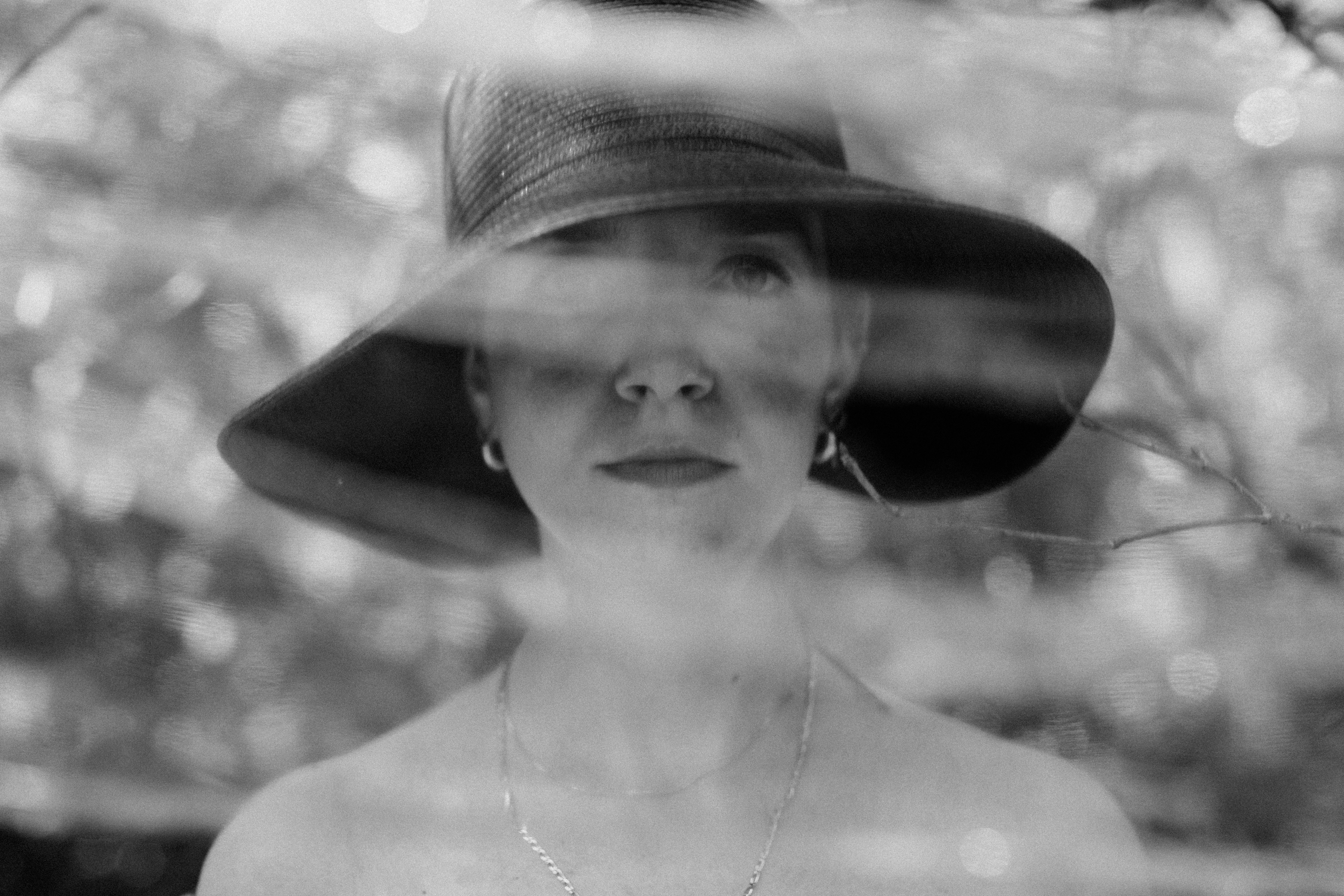 a woman wearing a hat looking through a window
