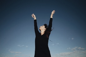 a woman in a black dress reaching up into the air
