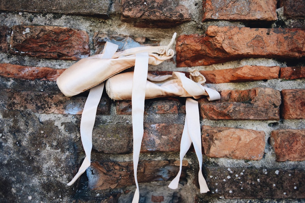 a pair of ballet shoes tied to a brick wall